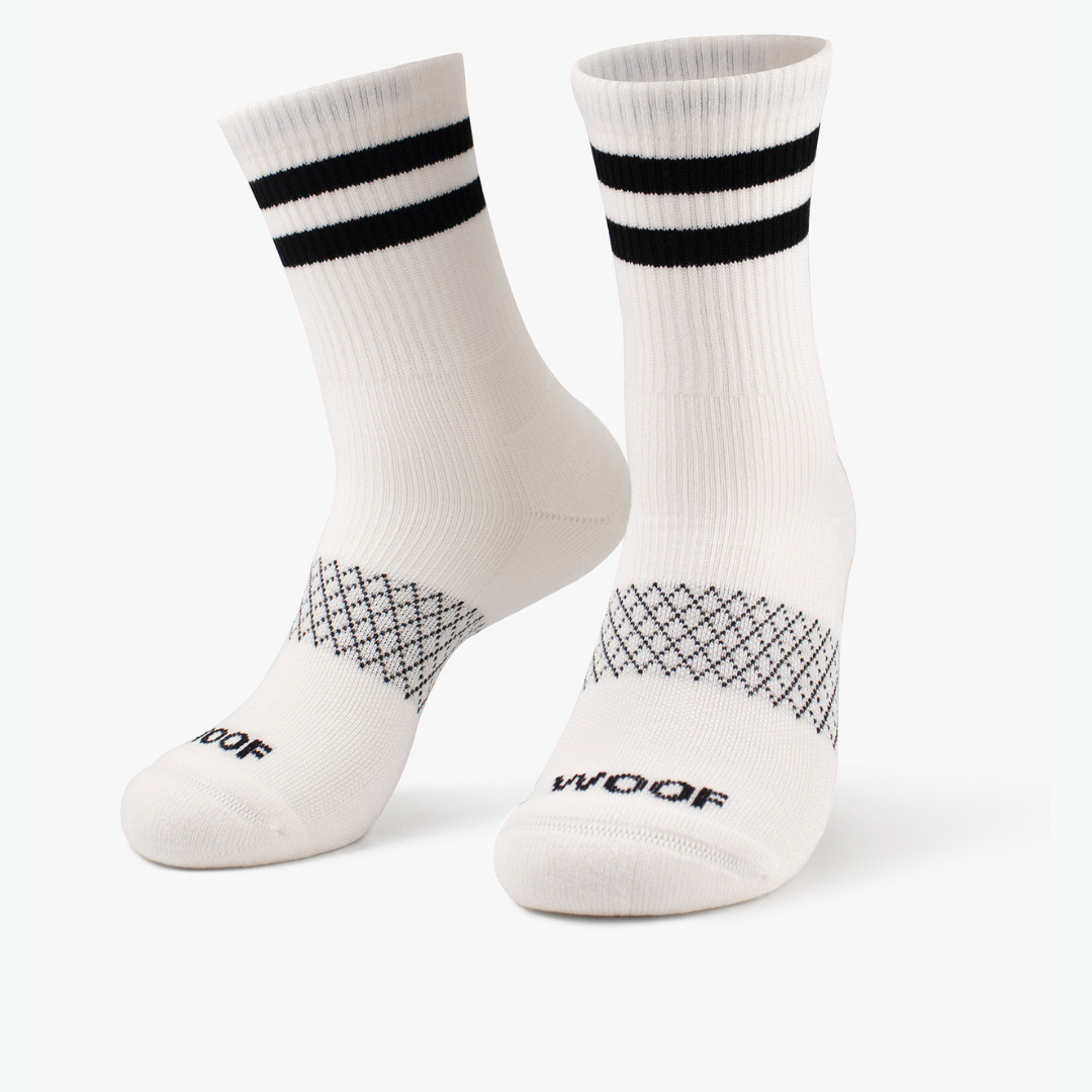 Pair of solid white crew-cut compression socks with double black cuff stripes standing against a plain background.